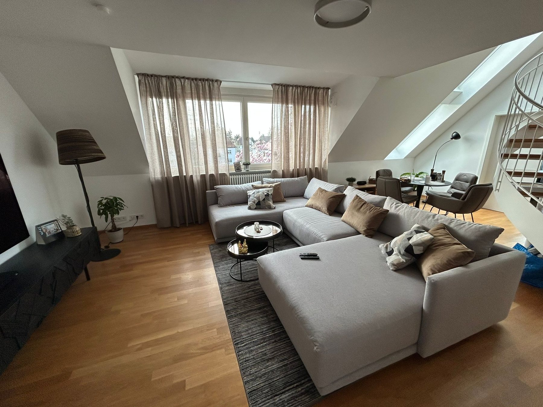 Wohn- und Essbereich eines Penthouses in Karlsruhe mit schwarzer Wendeltreppe