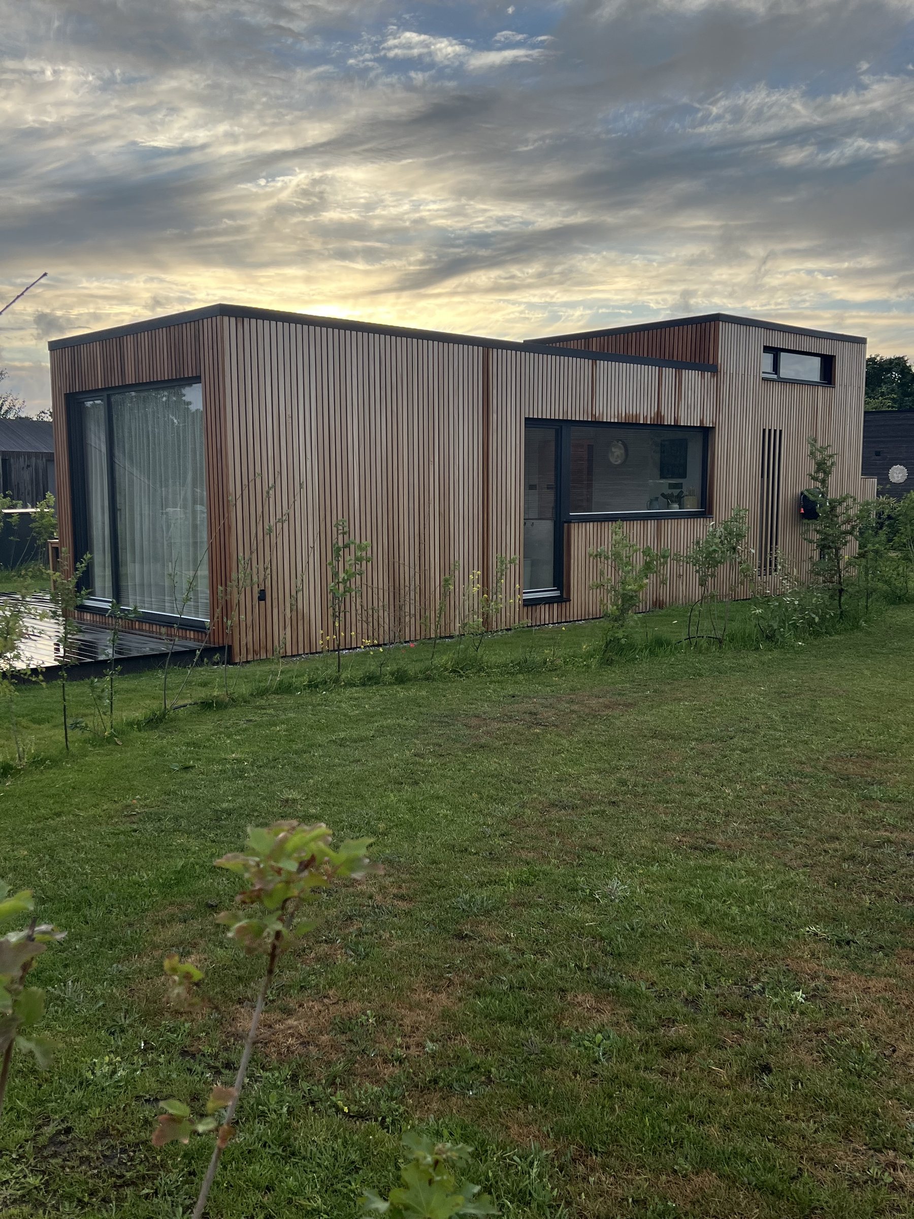 Tiny House mit Holzfassade auf einer Wiese in den Niederlanden im Abendlicht